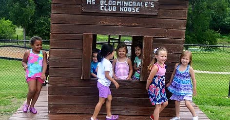 Children playing around a wooden playhouse