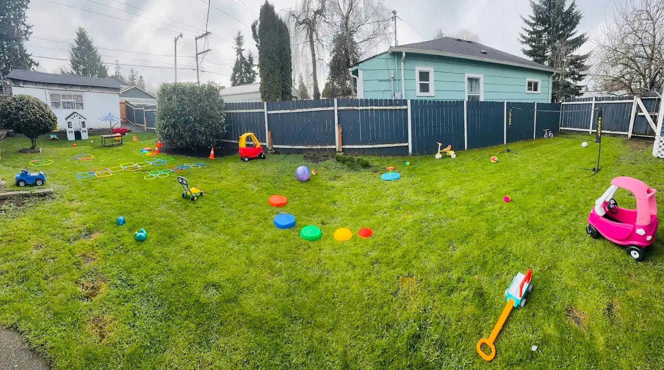 Grassy backyard with various colorful children's toys scattered around