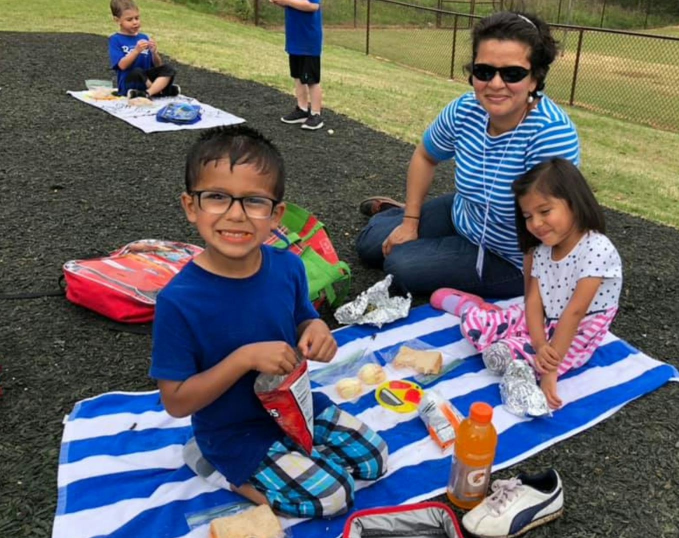 Adult and two children sitting on a blanket outdoors