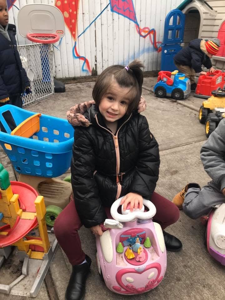 Child kneeling with a pink toy car