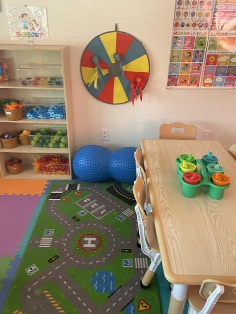 Classroom interior with shelving, play rug, and child-sized table
