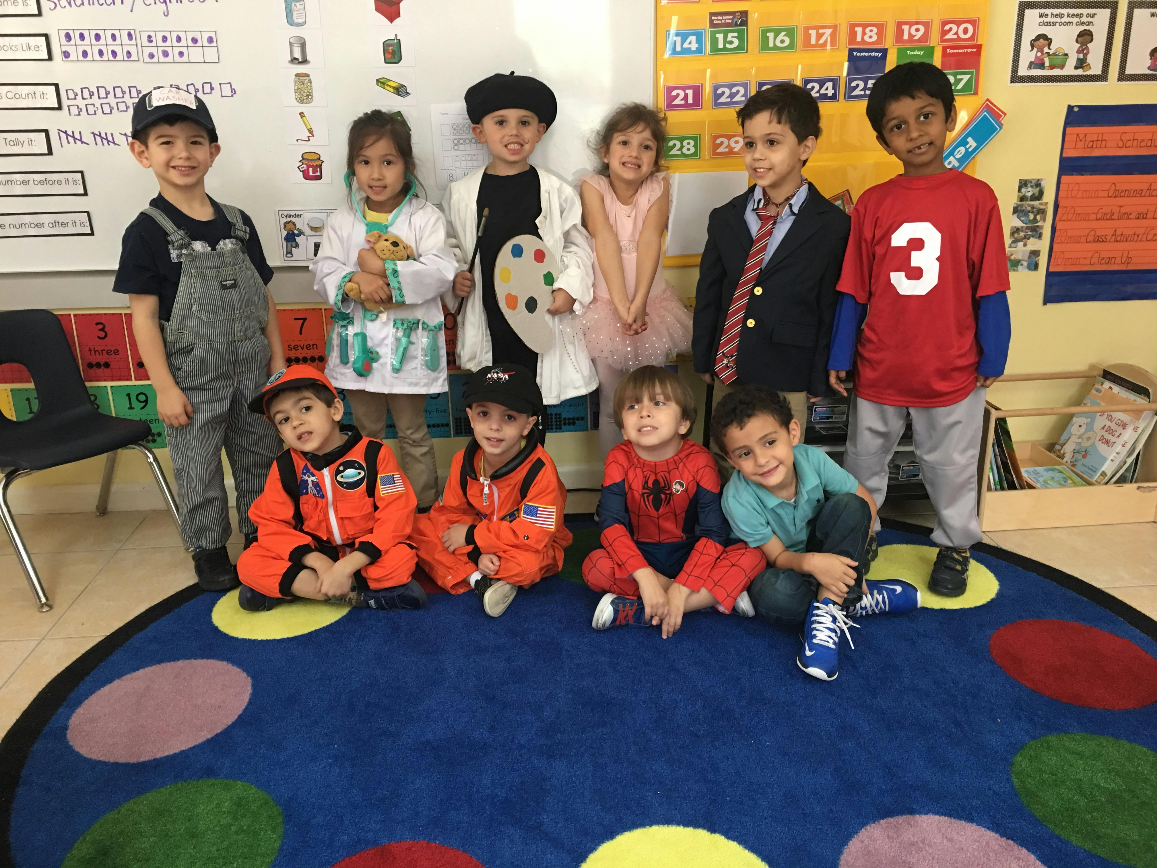 Group of children in various costumes standing and sitting on a colorful rug