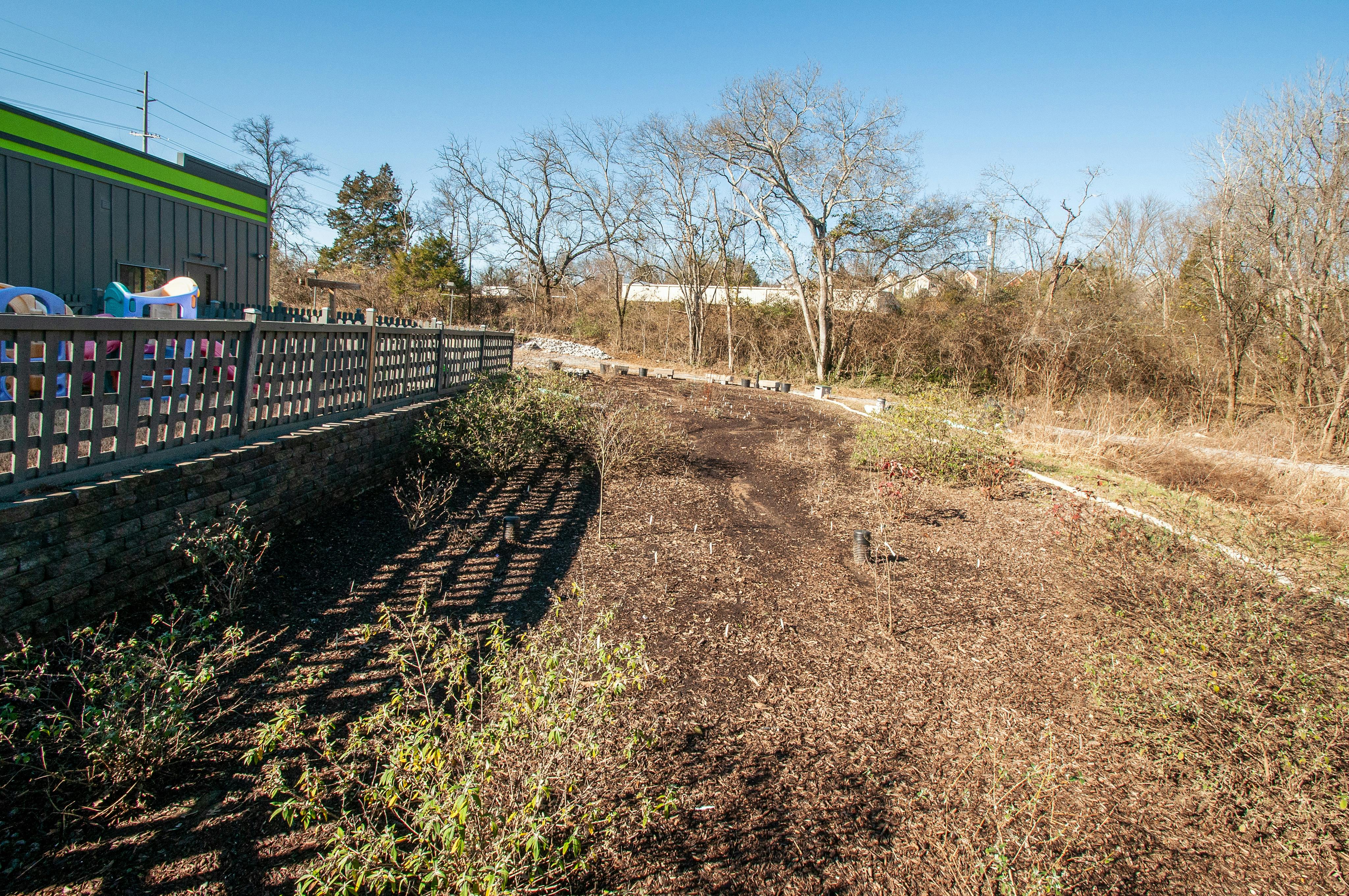 Building with a green roof next to a wooden fence and dry ground