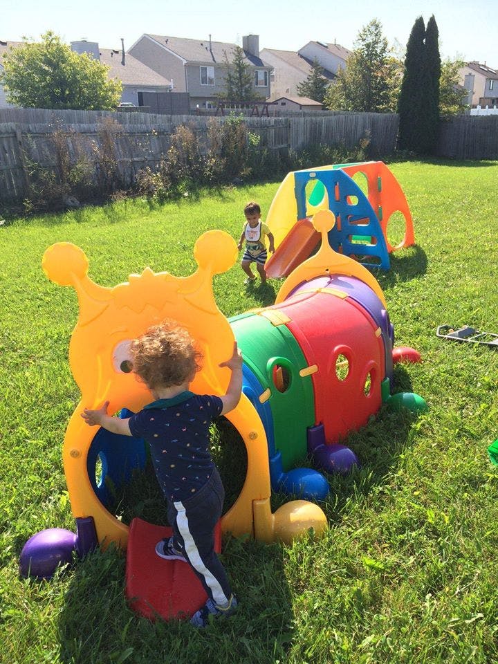 Child climbing into a colorful play tunnel in a grassy yard