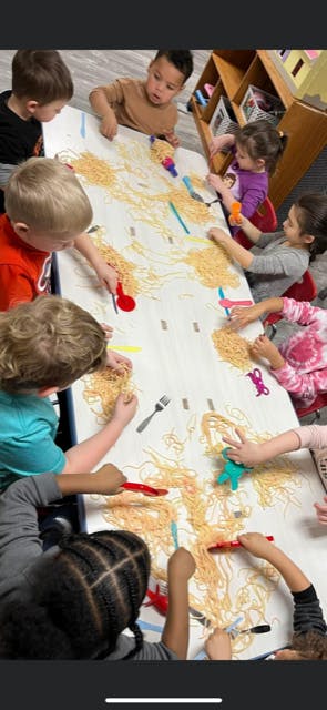 Children playing with spaghetti on a table