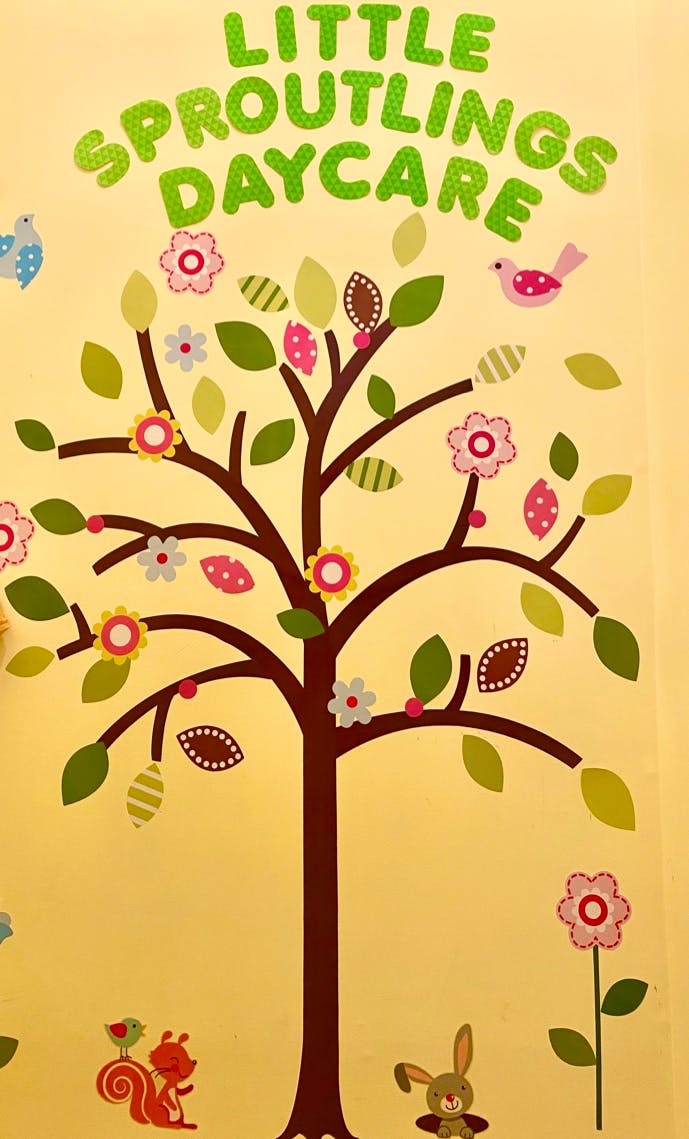 Little Sproutlings Daycare text above a tree with leaves, flowers, and animals