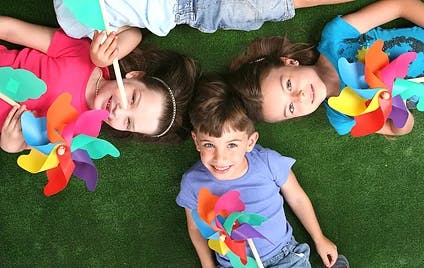 Three children lying on grass with pinwheels