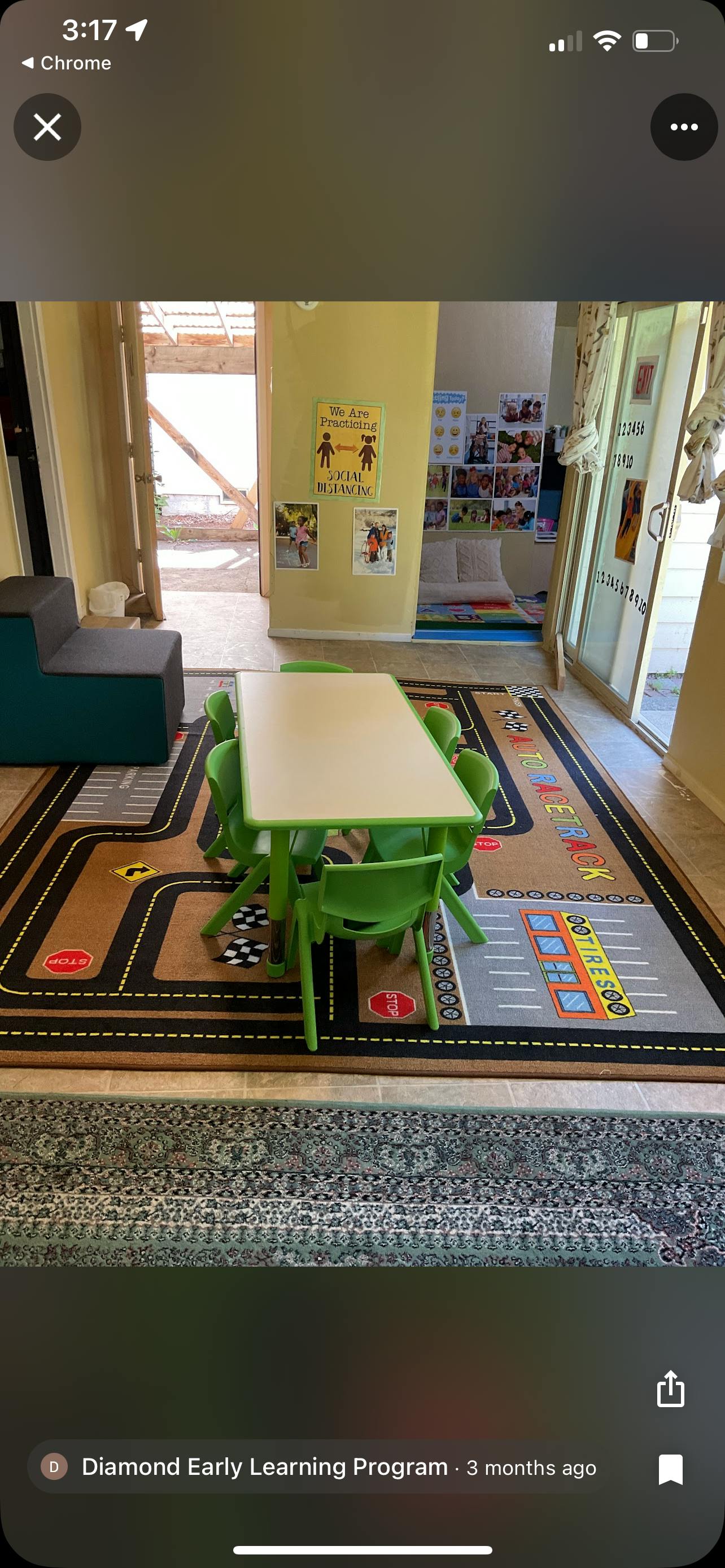 Small table with green chairs on a road-themed rug in a classroom