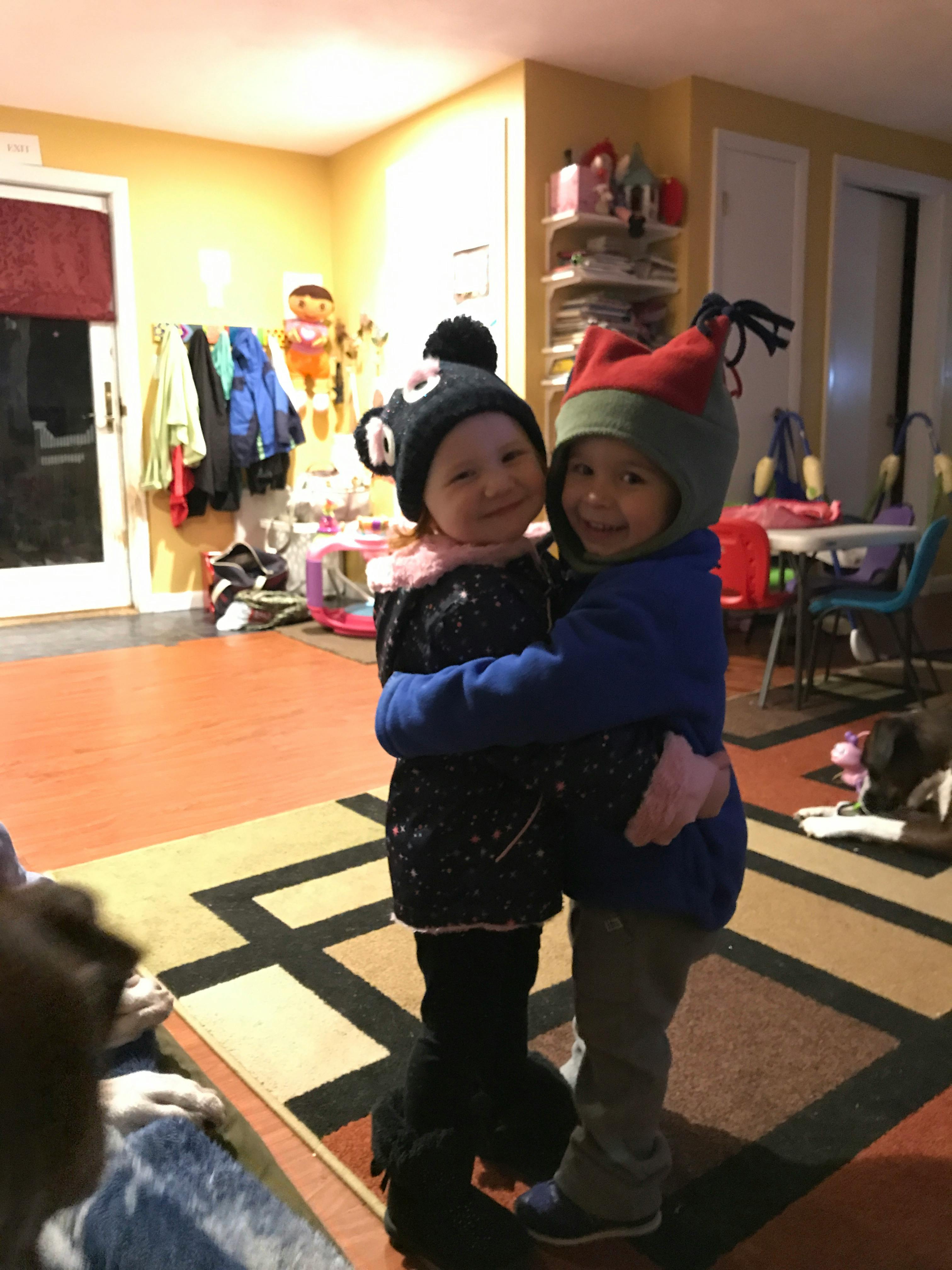 Two children in winter hats hugging