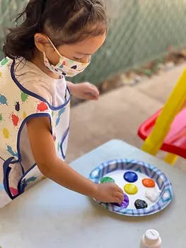 Child in a mask and smock painting