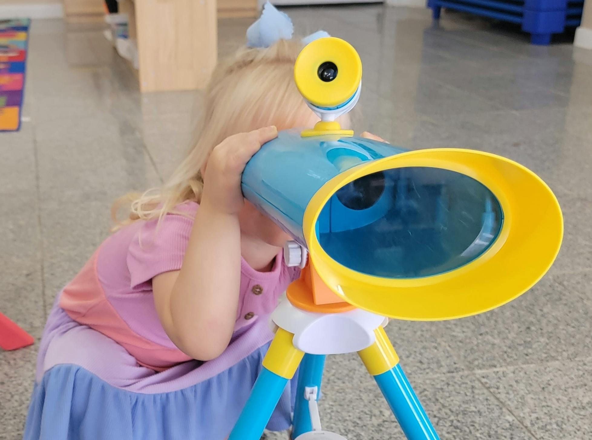 child looking through a toy telescope