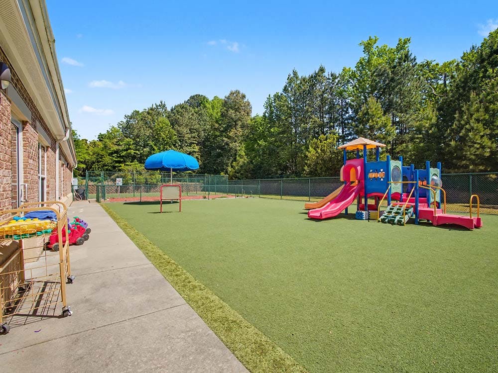 Colorful playground structure on artificial turf next to a building