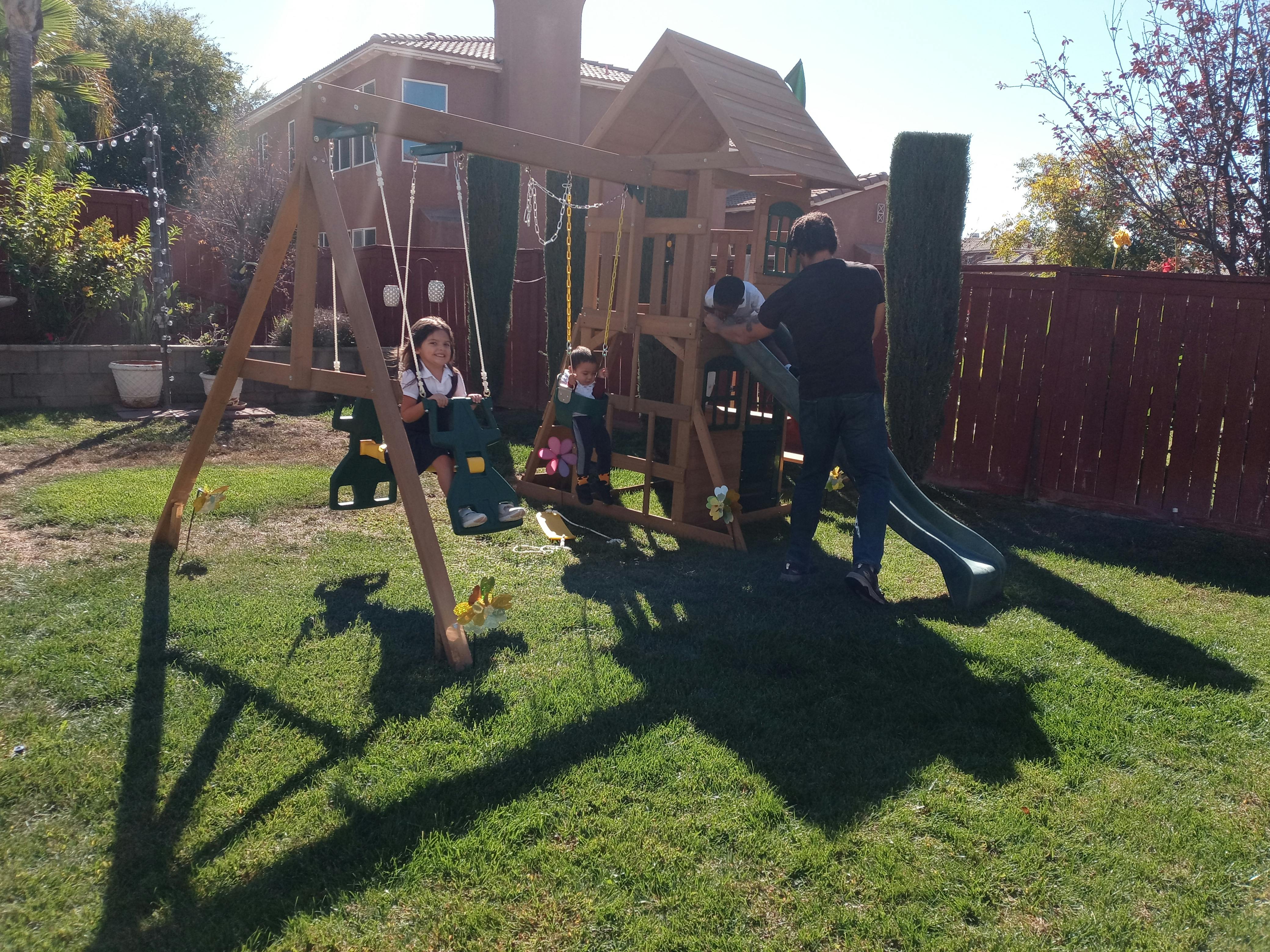 Children and adult on a backyard playset
