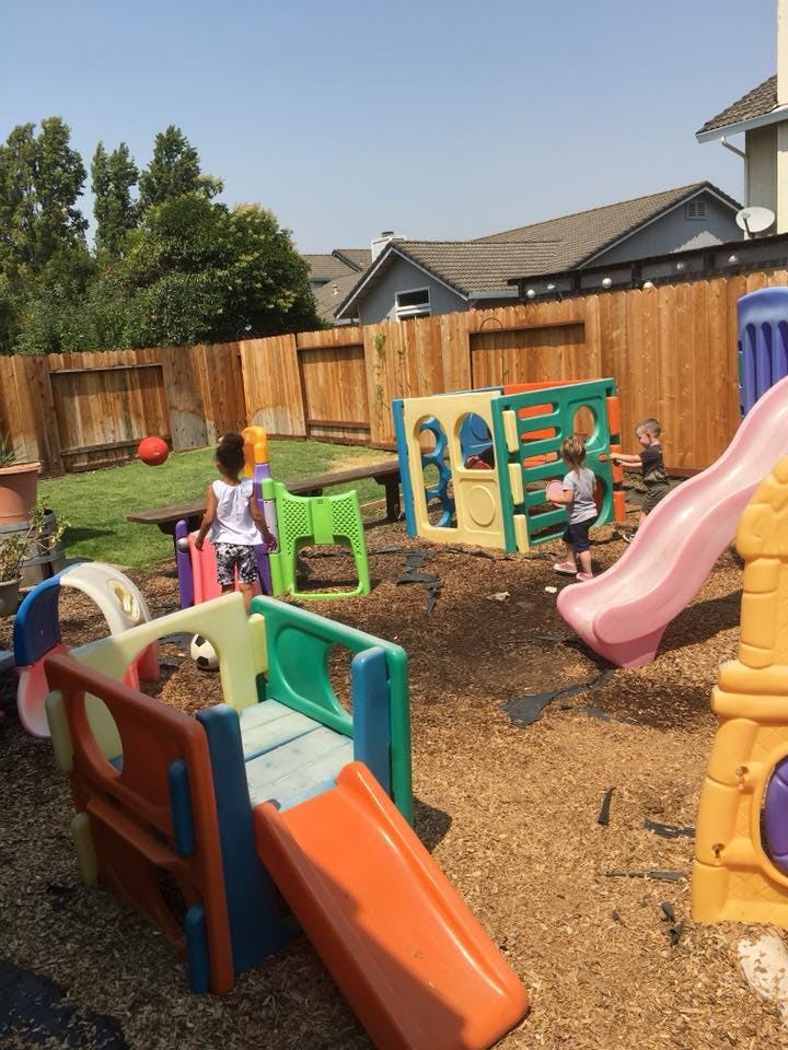 Children playing on colorful playground equipment in a backyard