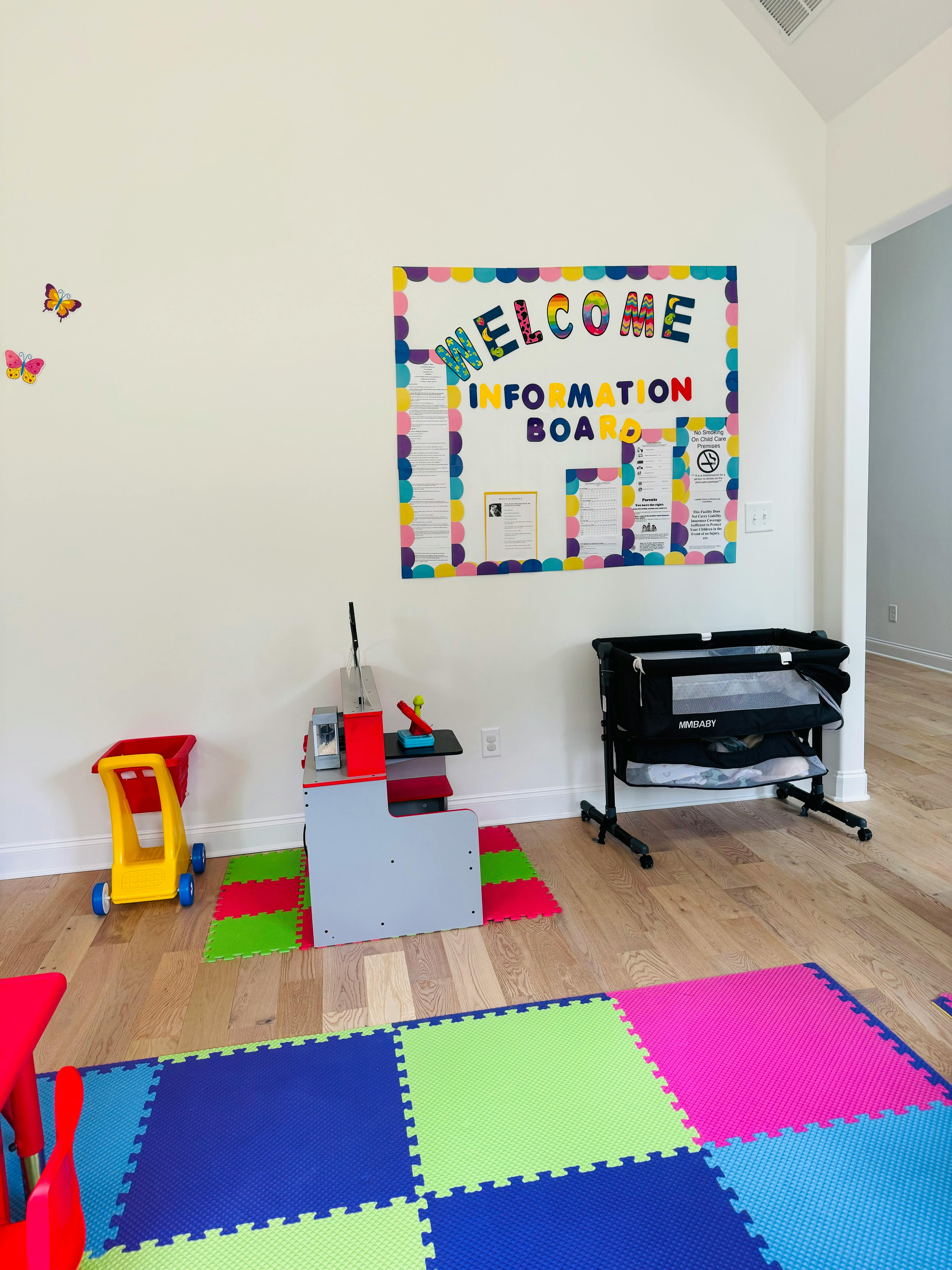 Playroom with a welcome information board, toys, and a playpen