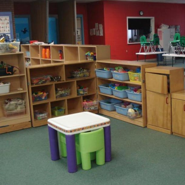 Classroom with shelves of toys and a small table with a green chair