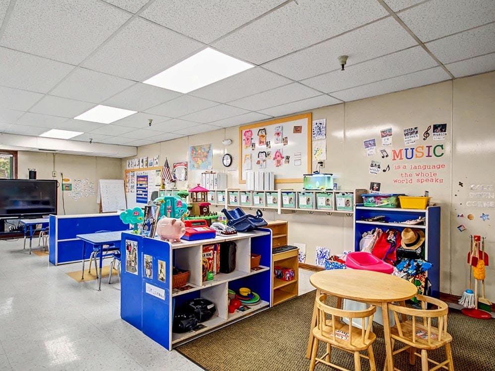 Classroom with child-sized tables and chairs, shelves, and learning materials