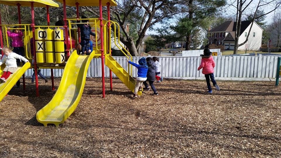 Children playing on a playground with slides and a tic-tac-toe game