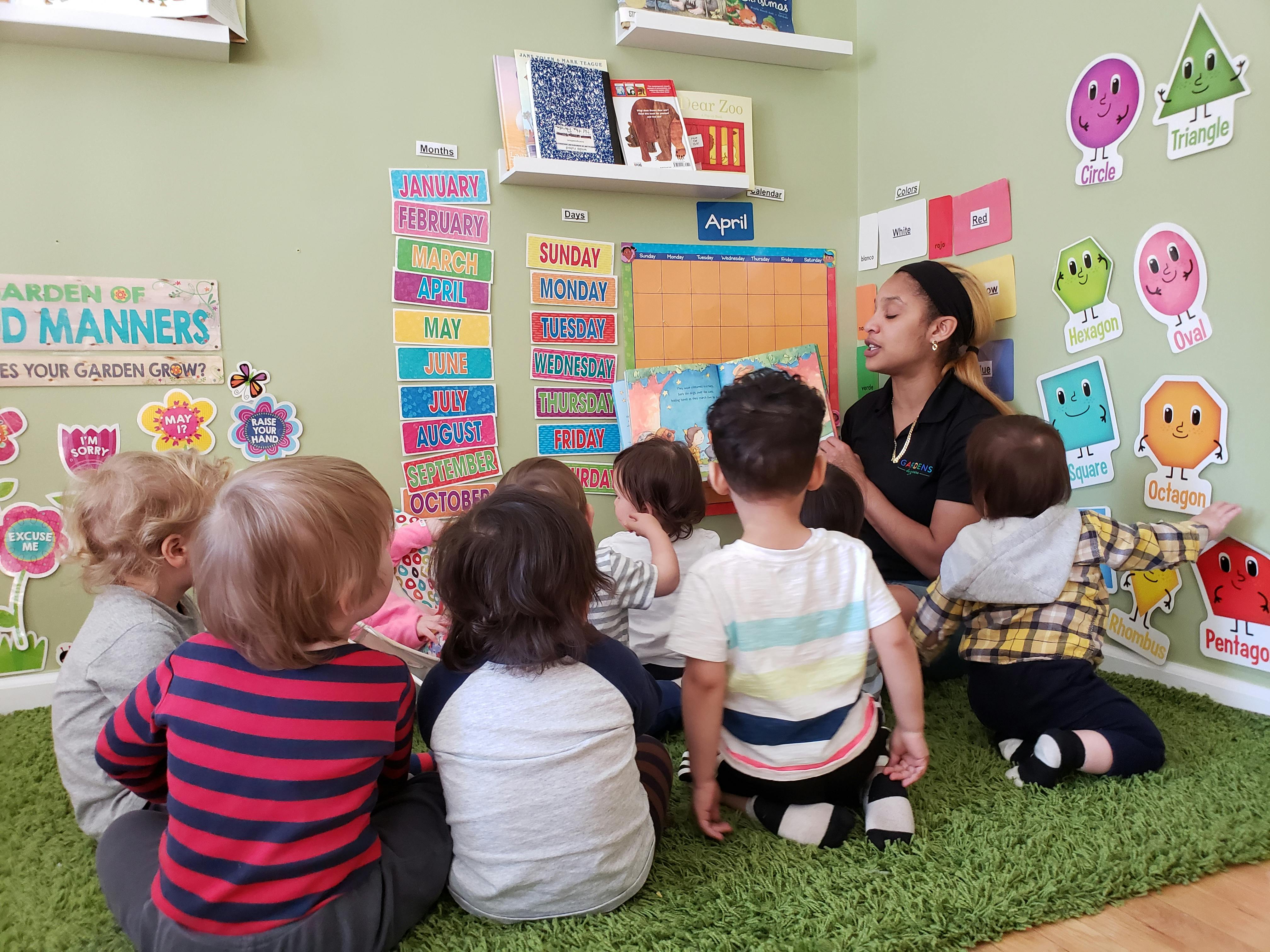 Adult person reading to a group of children in a classroom