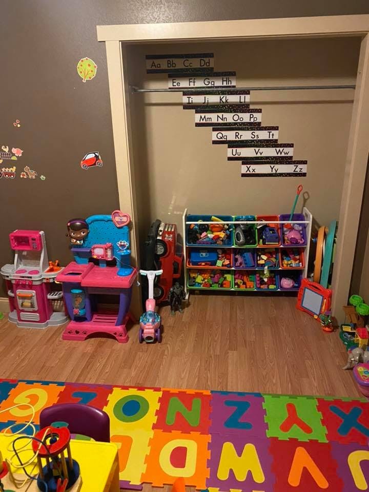 Playroom with alphabet wall decor, toy kitchen, and toy storage shelves