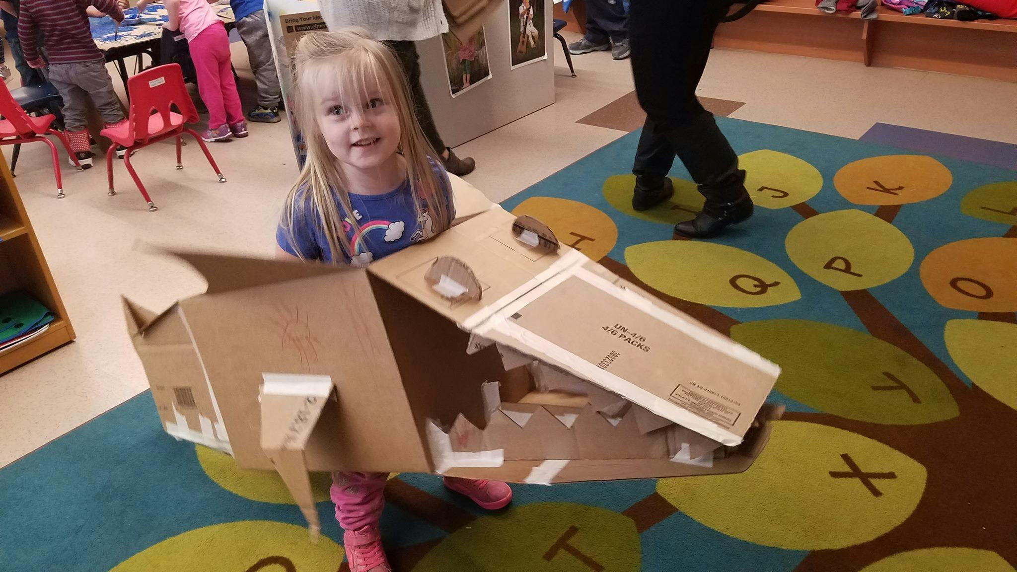 Child in a classroom wearing a cardboard box costume