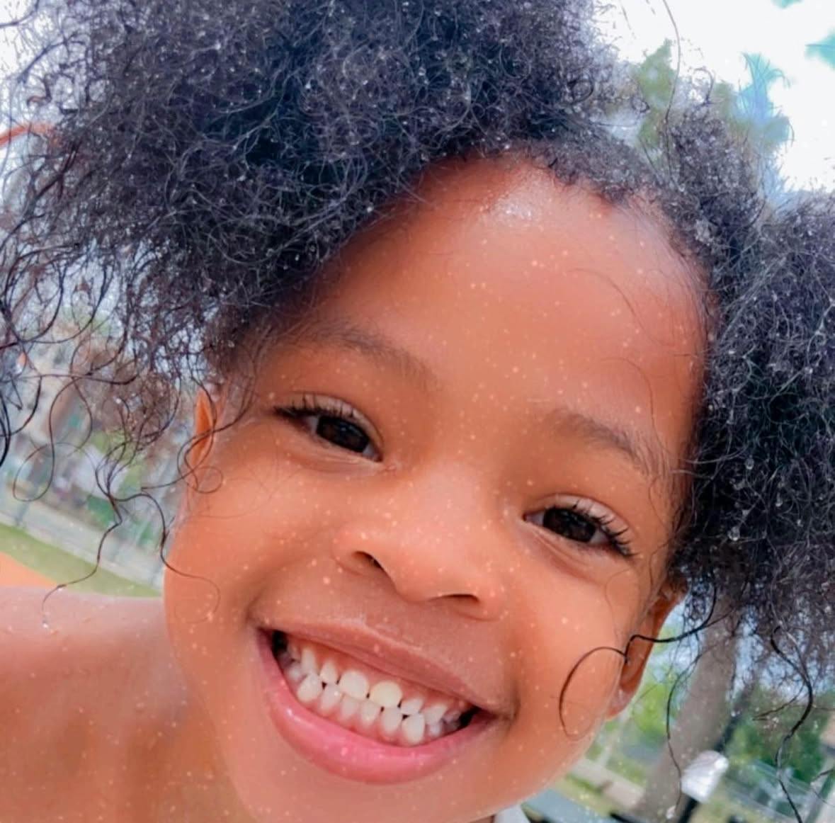 Child with curly hair smiling