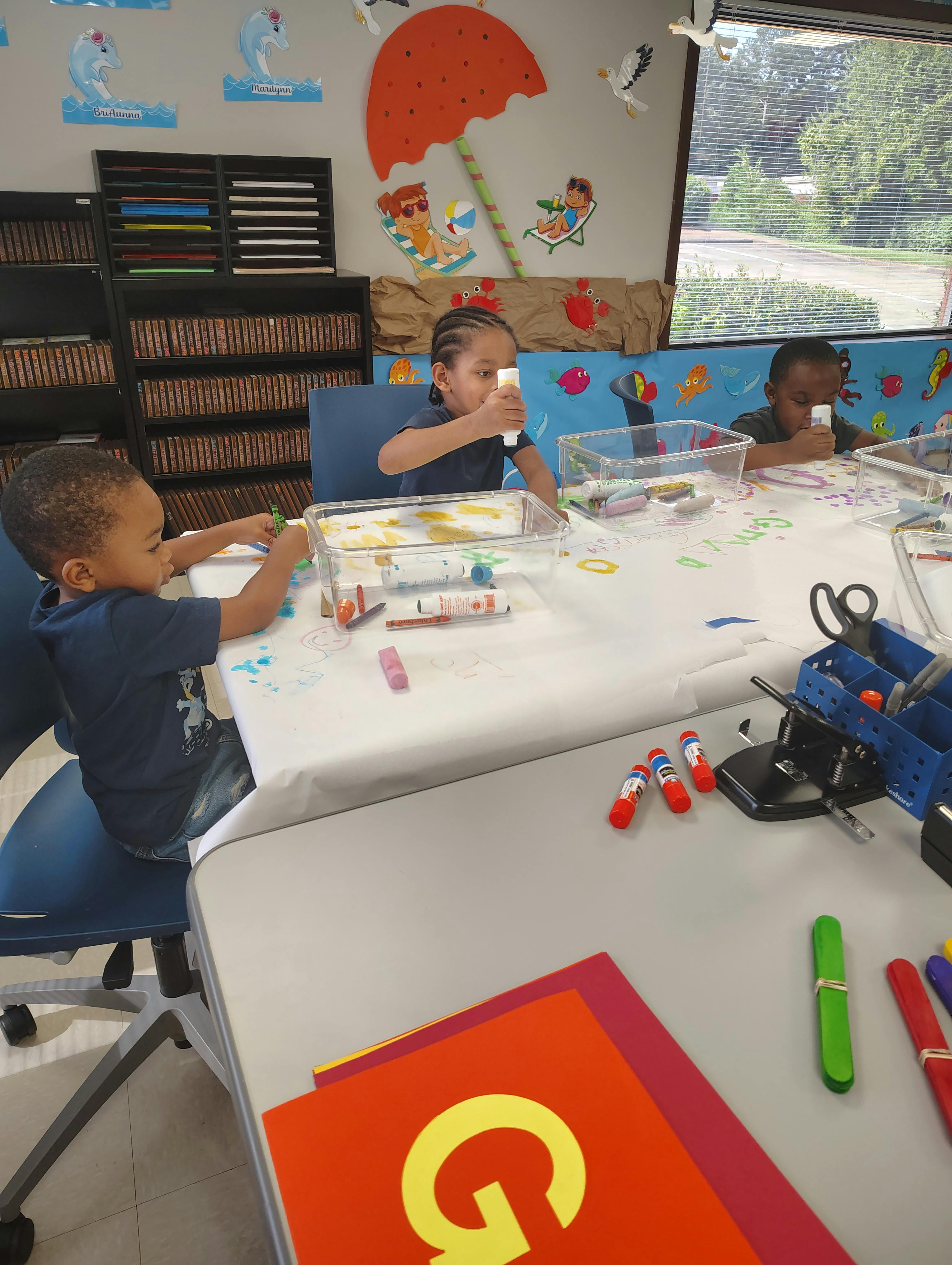 Three children at a table doing crafts in-class activities