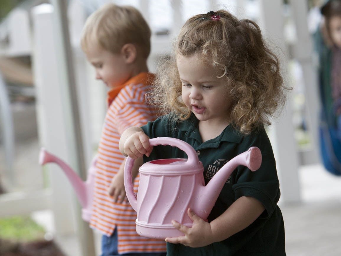 Child holding a watering can, another child in background