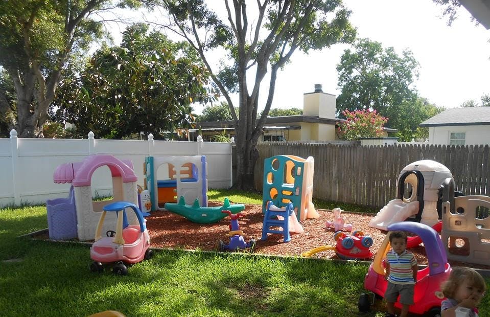 Child in a toy car on a playground with other play structures
