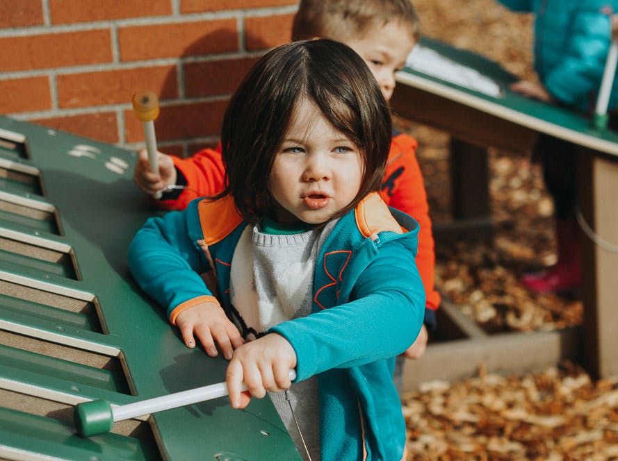 Child playing a large outdoor xylophone