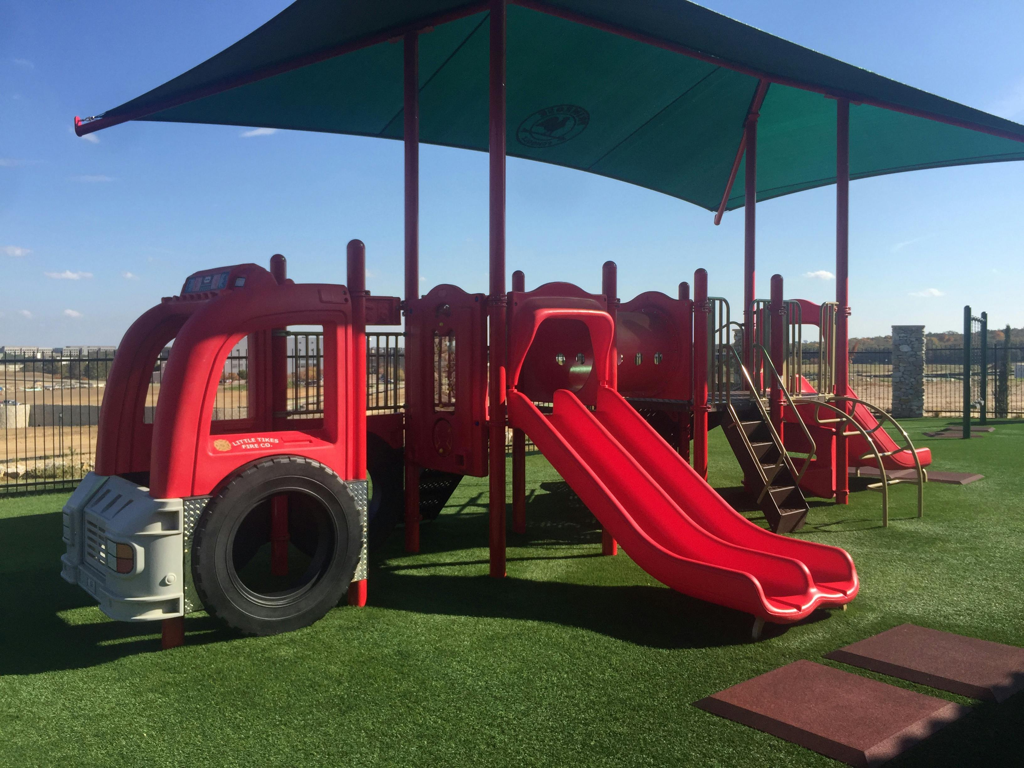 Red playground structure with slides and a truck-shaped climbing area