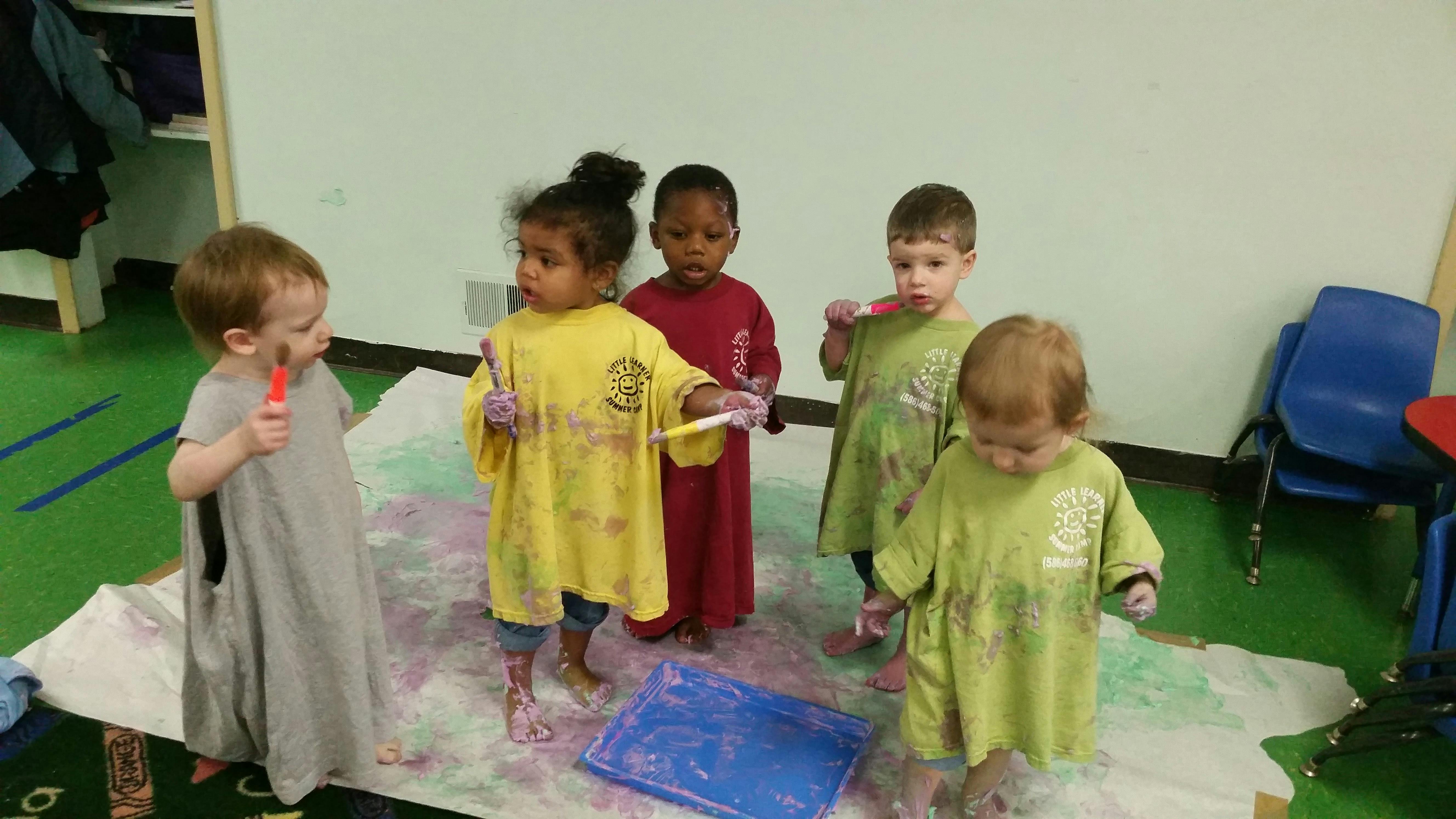 Children painting on a large sheet of paper on the floor