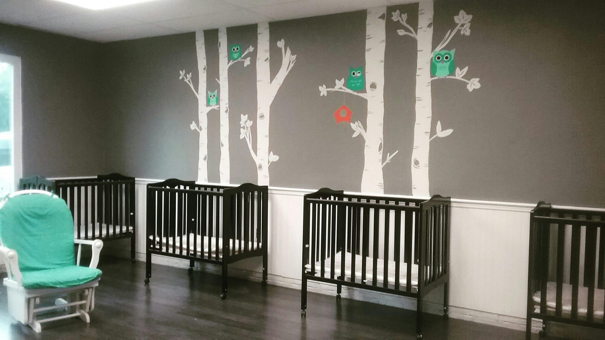 Nursery room with multiple cribs and a rocking chair