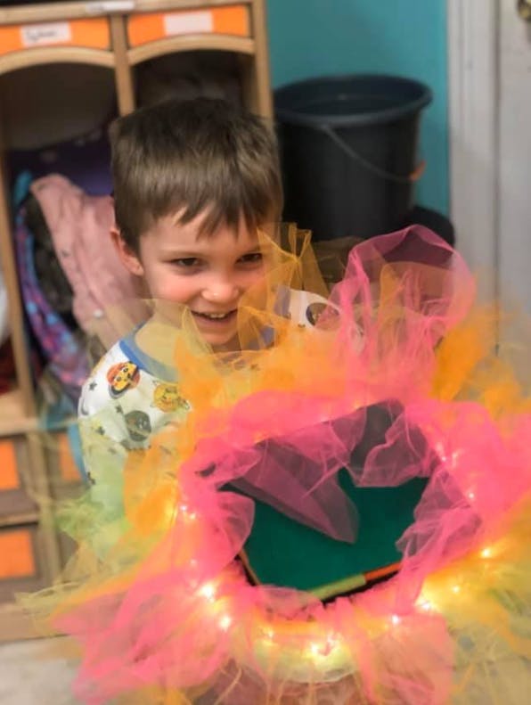 Child holding a colorful tulle decoration with lights
