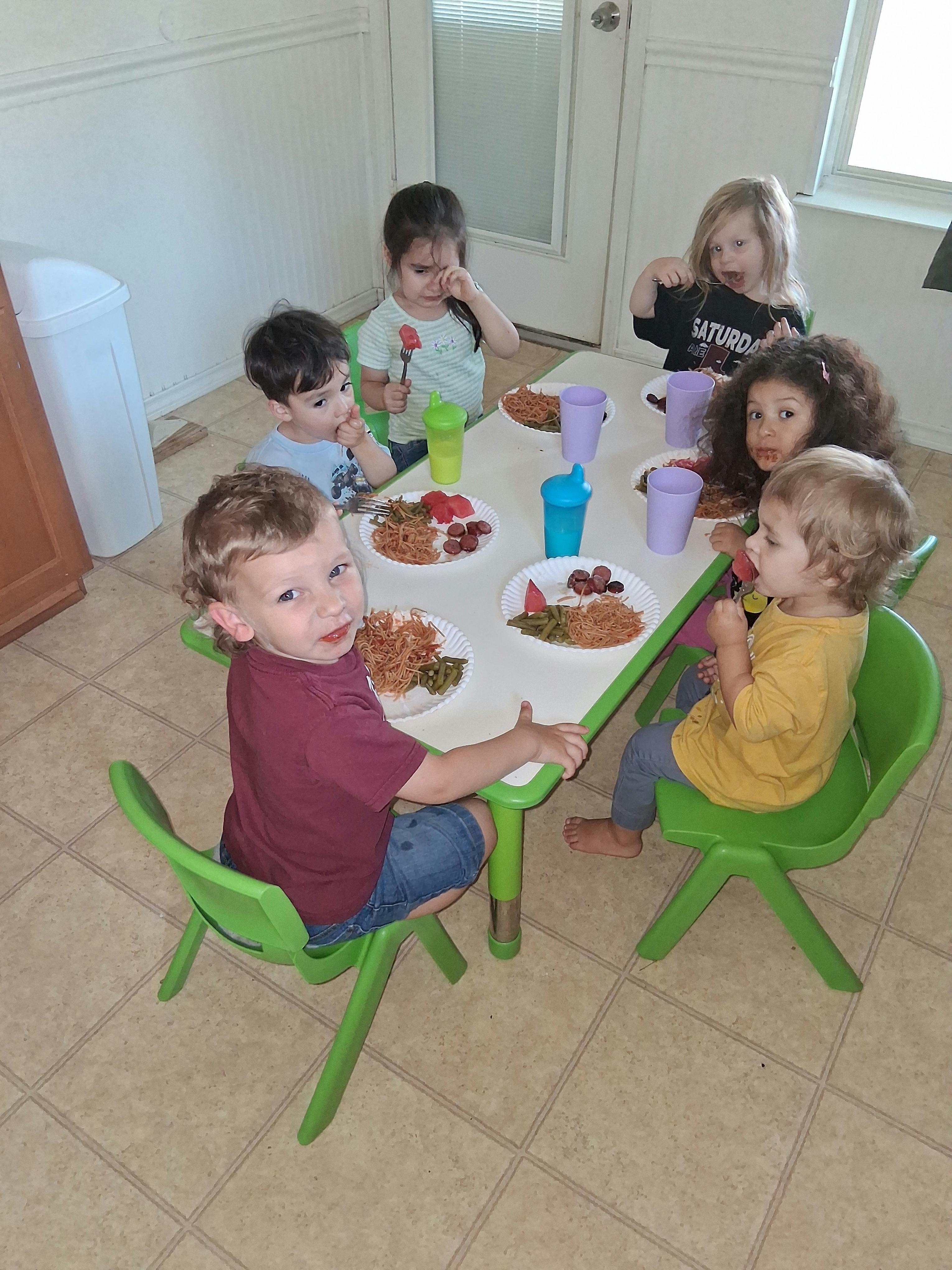 Five children eating a meal together at a small table