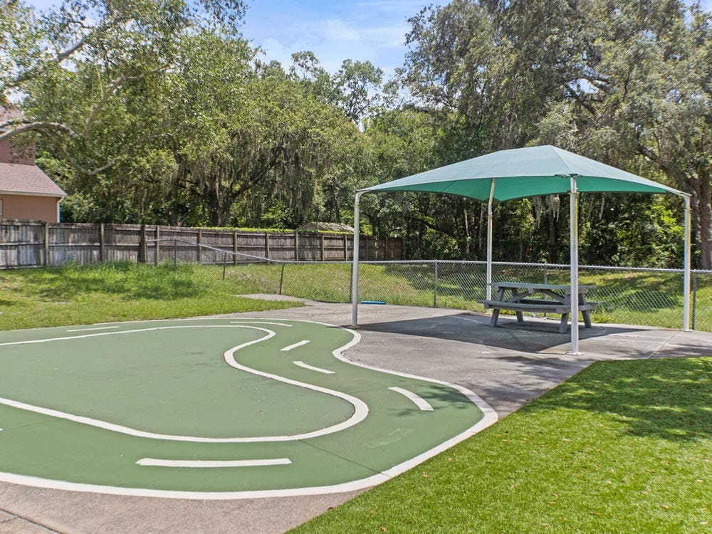 A green shaded picnic area next to a play path and grassy area