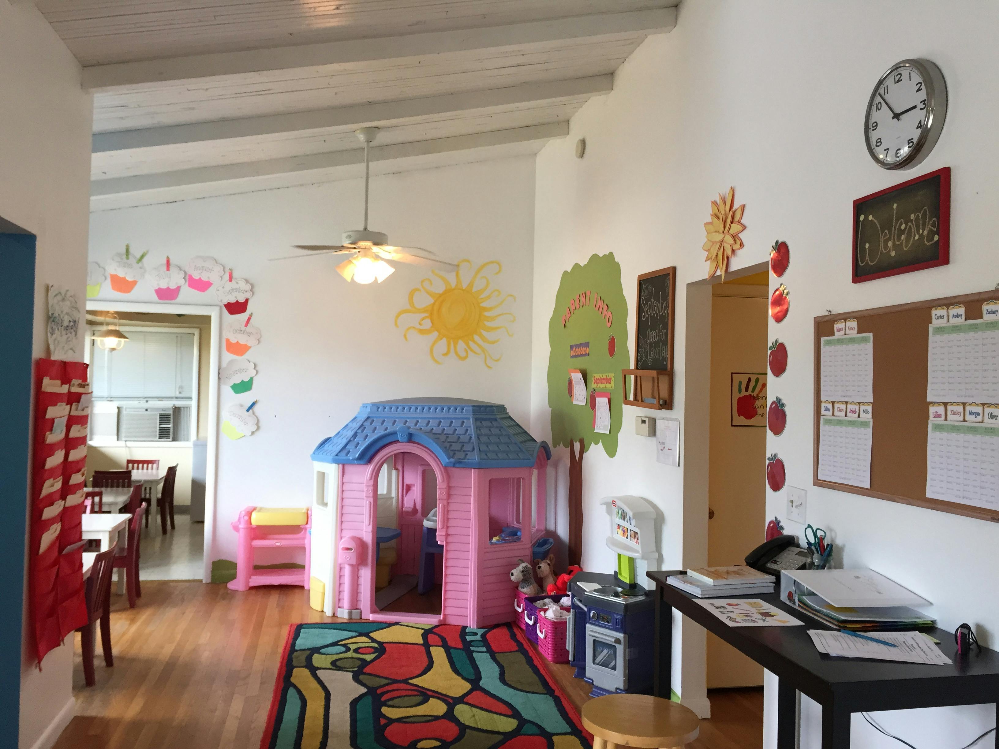 Playroom with a pink and blue playhouse, colorful rug, and wall decorations