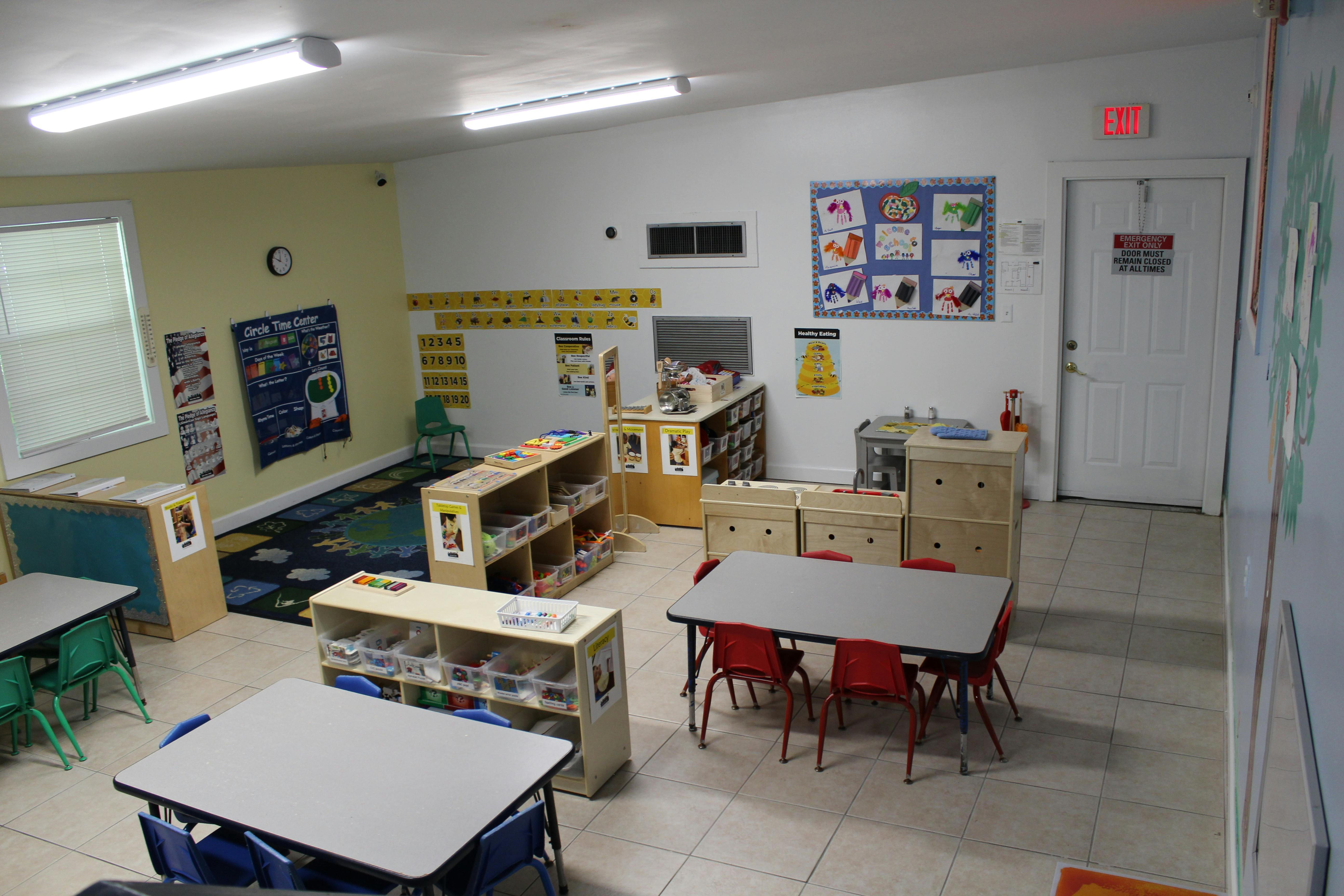 Classroom with small tables and chairs, shelves, and educational posters