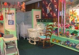 Nursery room with cribs, bassinet, rocking chair, and shelves of toys