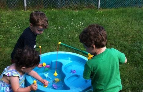 Three children playing with a water table and fishing toys