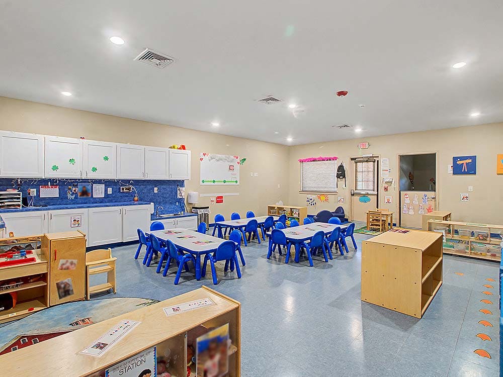 Empty colorful preschool classroom with small tables and chairs
