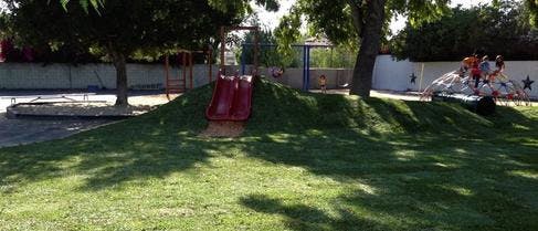 Red slide on a grassy mound in a playground