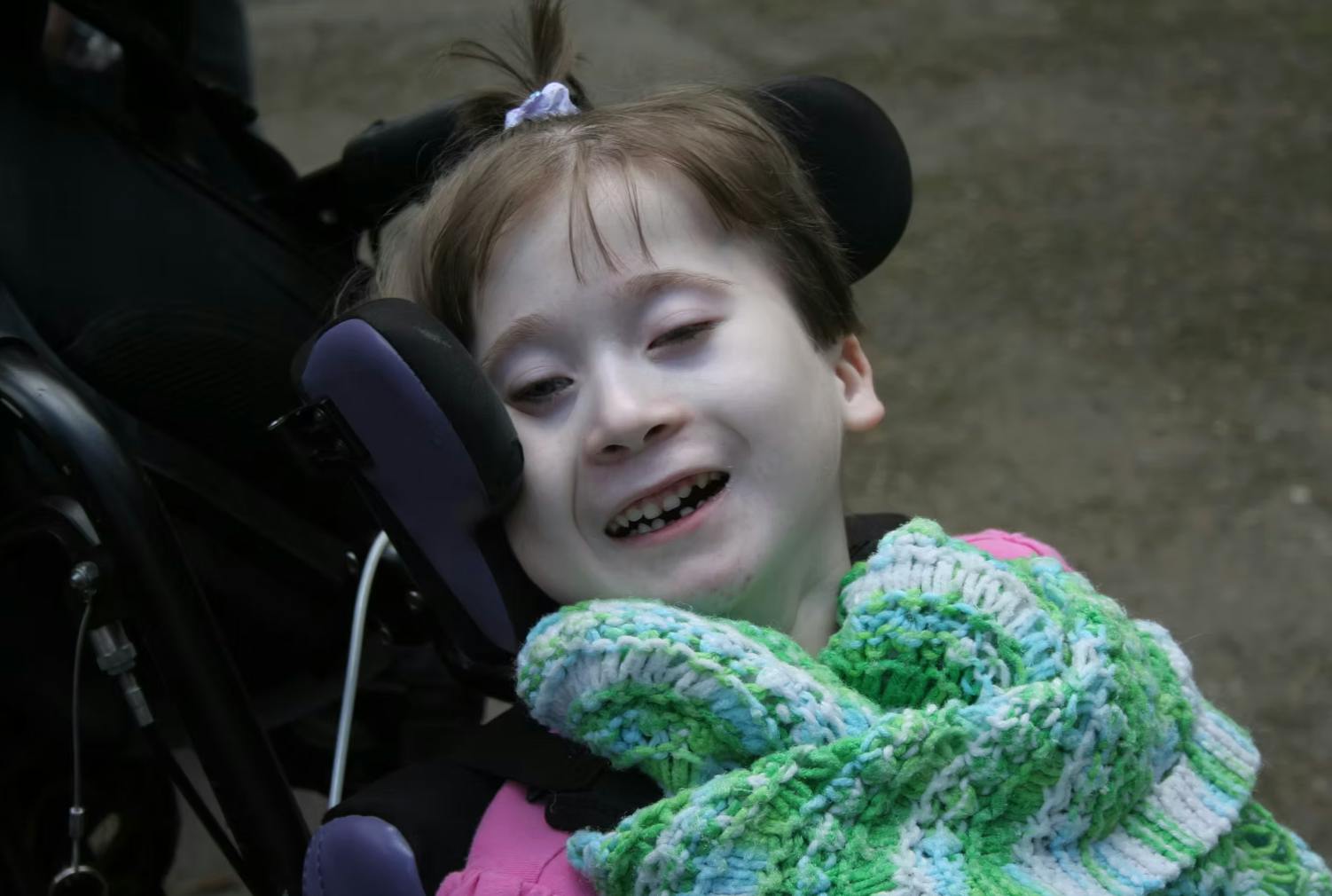 Child in a wheelchair with a green and white blanket