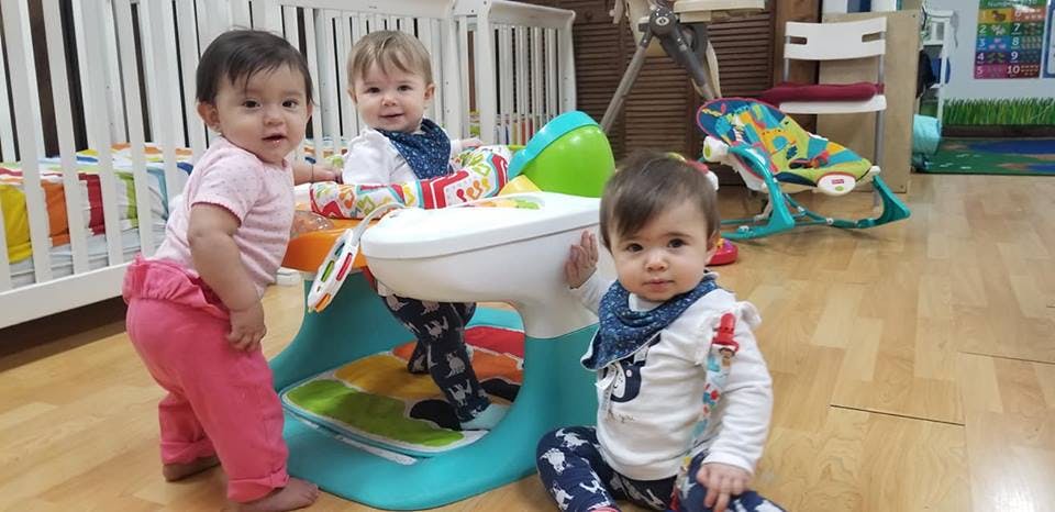 Three children playing with a baby activity center