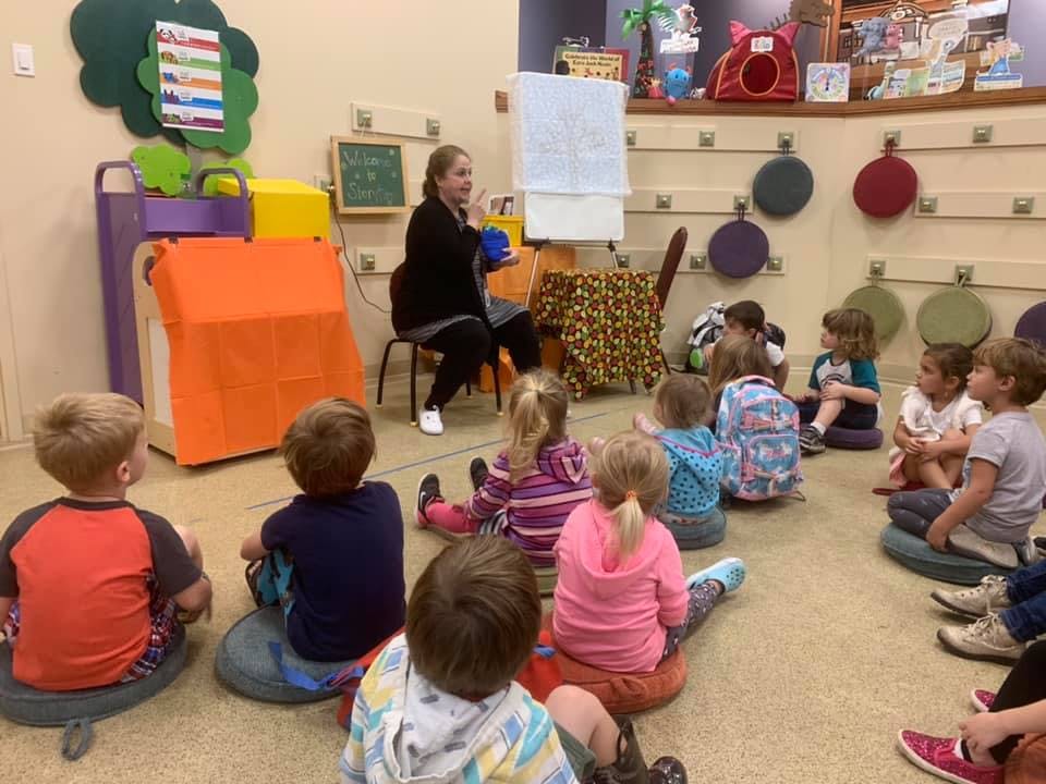 Adult leading a group of children in a classroom activity