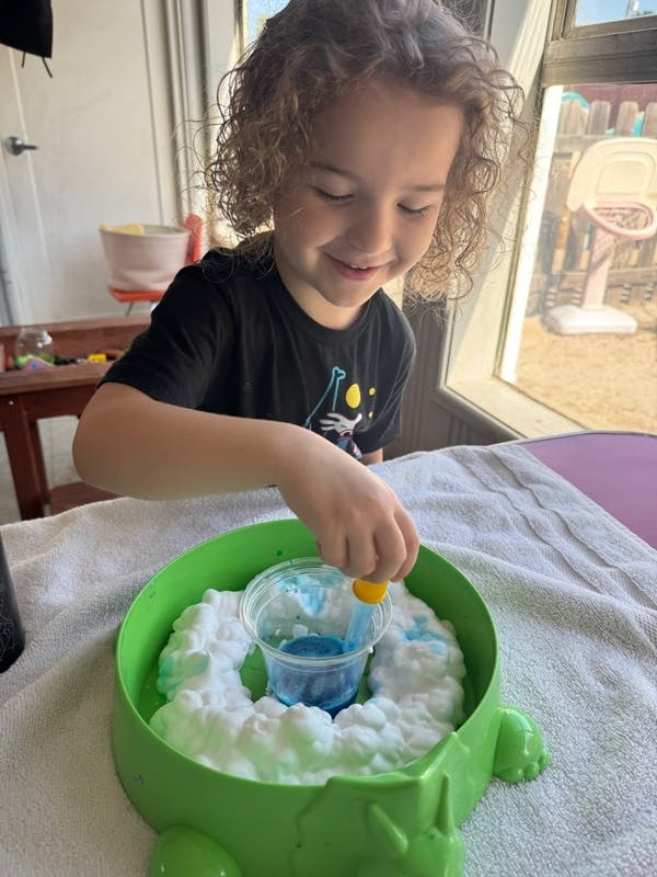 Child playing with a science experiment involving blue liquid and white foam