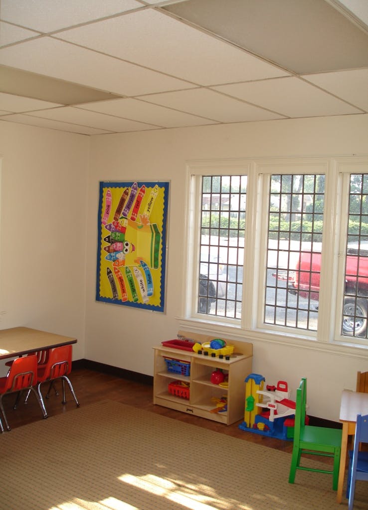 Classroom with tables, chairs, and a bulletin board with crayon cutouts