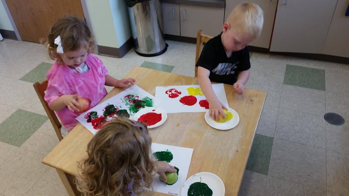 Three children doing potato printing at a table