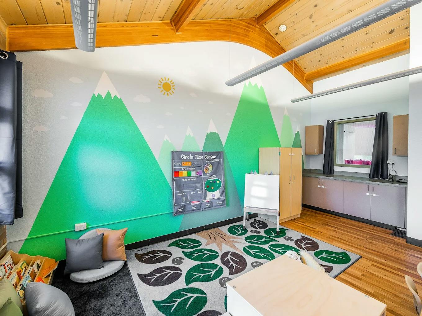 Classroom interior with mountain mural and a circle time center wall chart