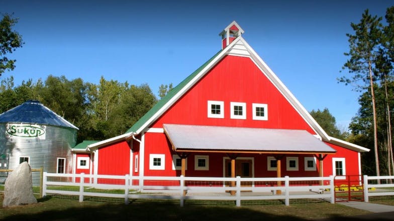 Red barn with a green roof and a silver grain silo
